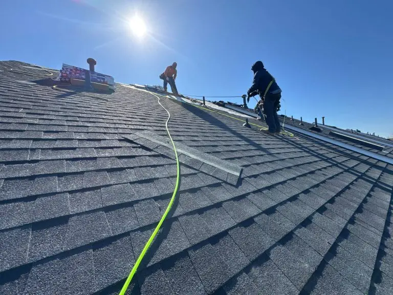 Roofers working on a dark asphalt-shingle roof